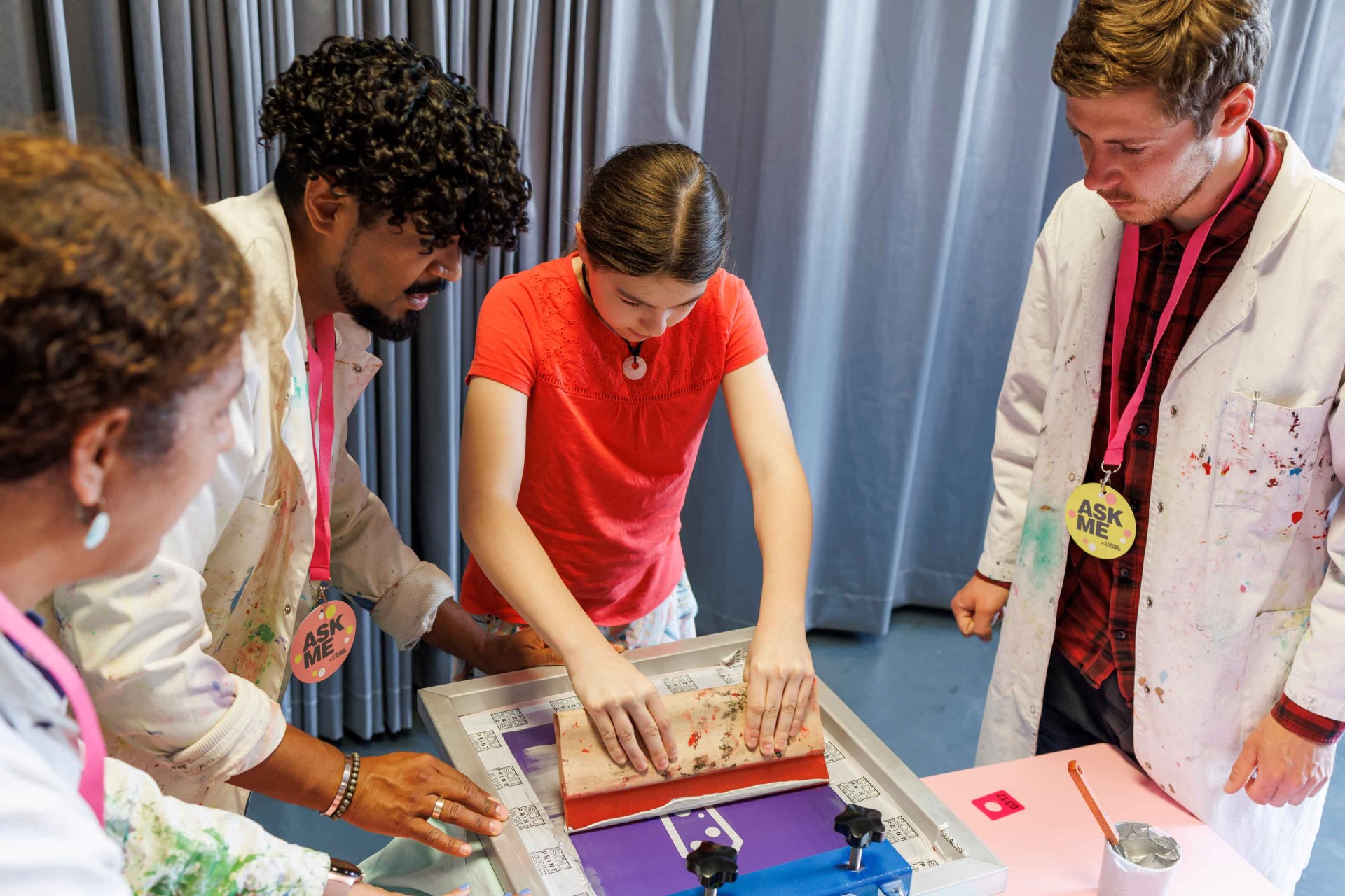 Children and adults are collaboratively working on a creative printing project in a studio.