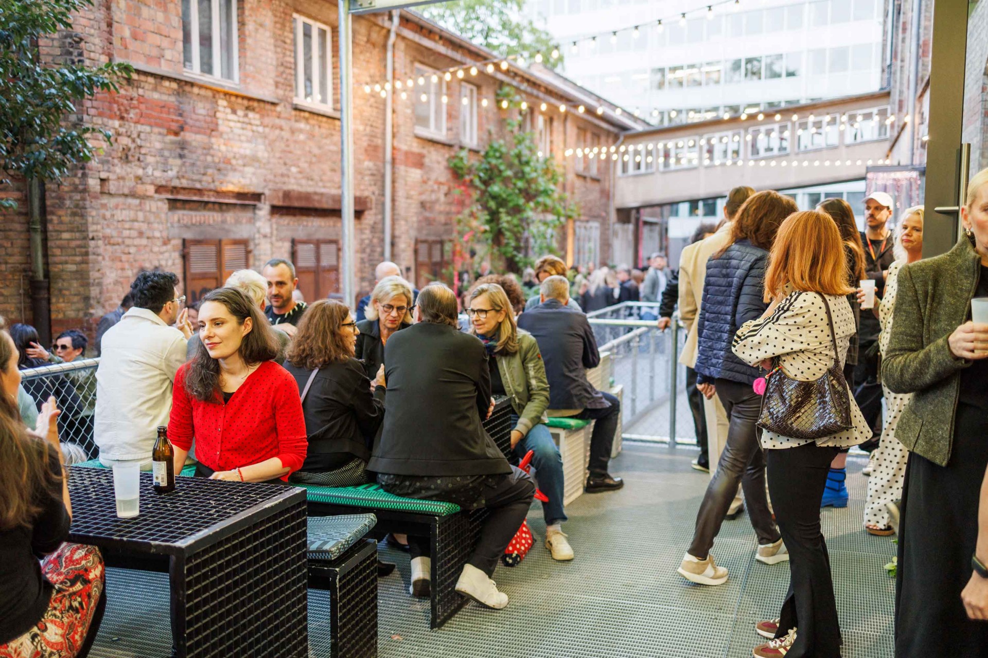 Social gathering in an urban setting, with people at tables and a cozy atmosphere.
