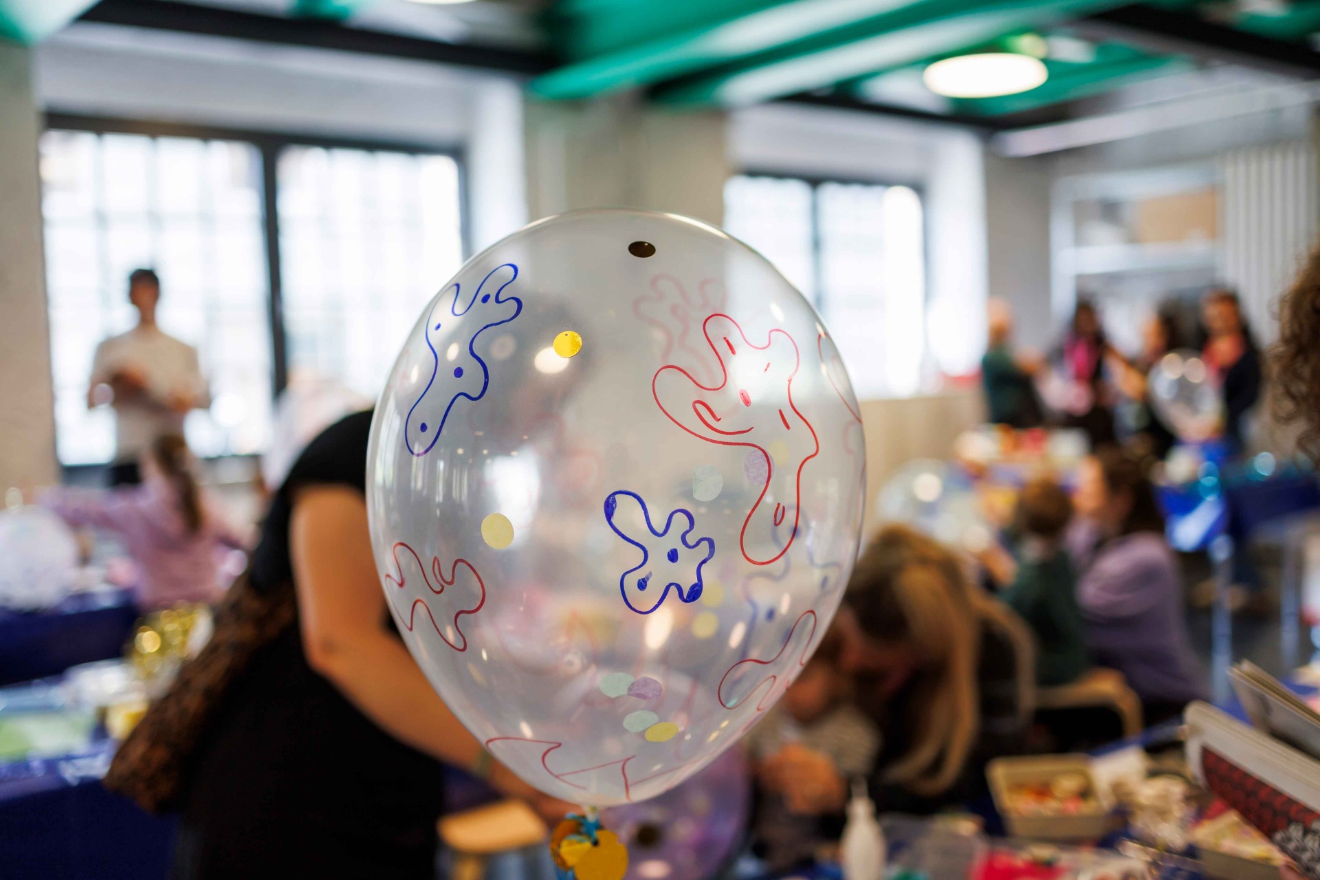 A balloon with colorful patterns in a lively room filled with people and decorations.