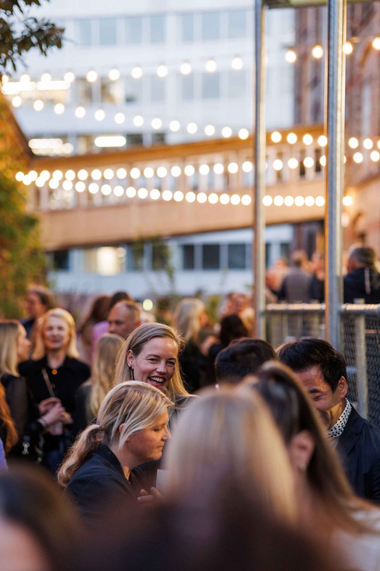 Crowd at an outdoor celebration, surrounded by lights and a relaxed atmosphere.