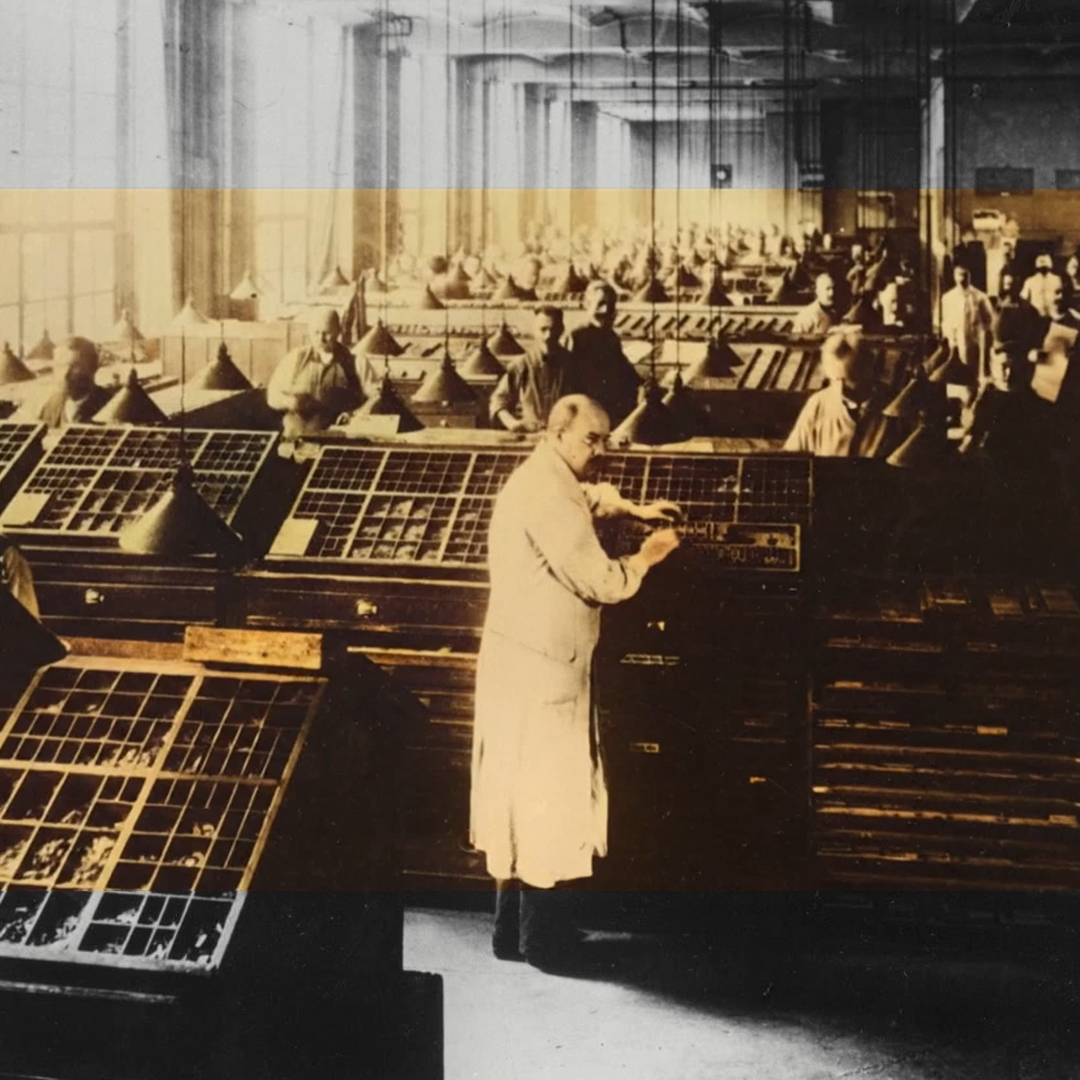 Historisches Bild einer Druckerei mit Arbeiter*innen an Setzmaschinen und Arbeitstischen.
